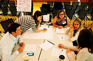 Attendees put their heads together in a breakout group at the DFMCH’s opportunities conference. More photos.