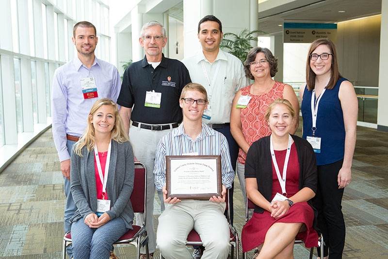 Representatives from the DFMCH and the FMIG receive the AAFP’s Program of Excellence award. Back row, from left: SMPH student Cameron Blegen; DFMCH Office of Medical Student Education Director David Deci, MD; SMPH student Manuchehr Habibi; DFMCH Office of Medical Student Education program coordinator Joyce Jeardeau; SMPH student Kristin Magliocco. Front row, from left: SMPH students Nicole Altman, Willem Schott and Lindsey Boyke. (Photo: AAFP)