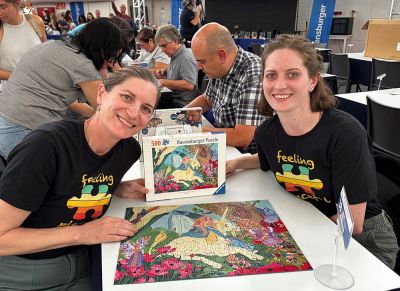 two people at a table completing a puzzle.