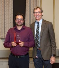 Andrew Quanbeck, PhD, holds award, standing next to David Rakel, MD.