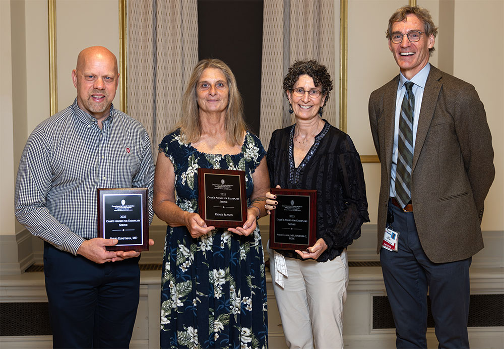 Group photo with four people. Winners are holding awards.