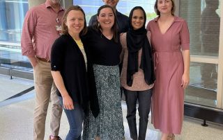 Six members of the PROTEA Team stand in a sunny hallway.